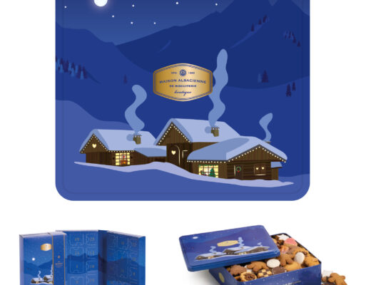 Une boîte bleue festive et un calendrier de l'Avent représentent un village d'hiver enneigé la nuit, avec des montagnes, des étoiles et des cheminées fumantes. La boîte est ouverte, laissant apparaître des biscuits assortis à l'intérieur.